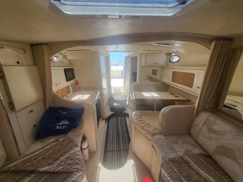 Slide: The Image of Interior of 1999 Sea Ray 290 Sundancer boat, featuring cozy seating and kitchenette. - 11