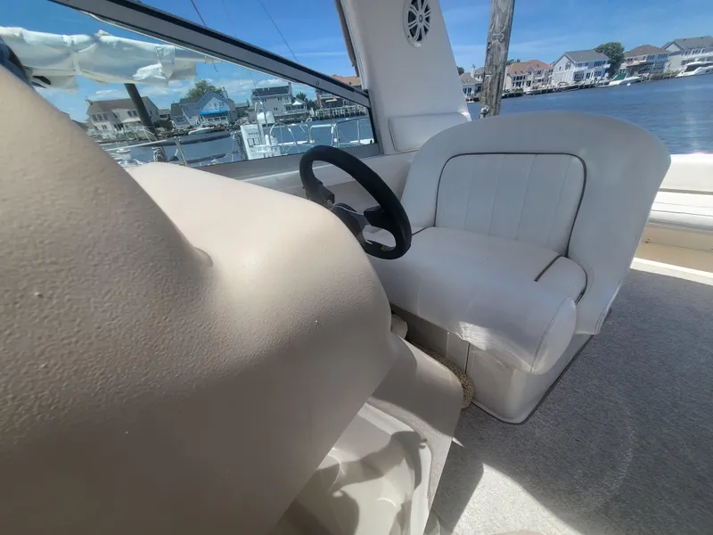 Slide: The Image of 1999 Sea Ray 290 Sundancer helm with white seating and waterfront view. - 17