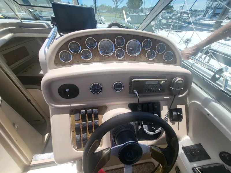 Slide: The Image of 1999 Sea Ray 290 Sundancer helm with gauges, steering wheel, and control panel. - 26