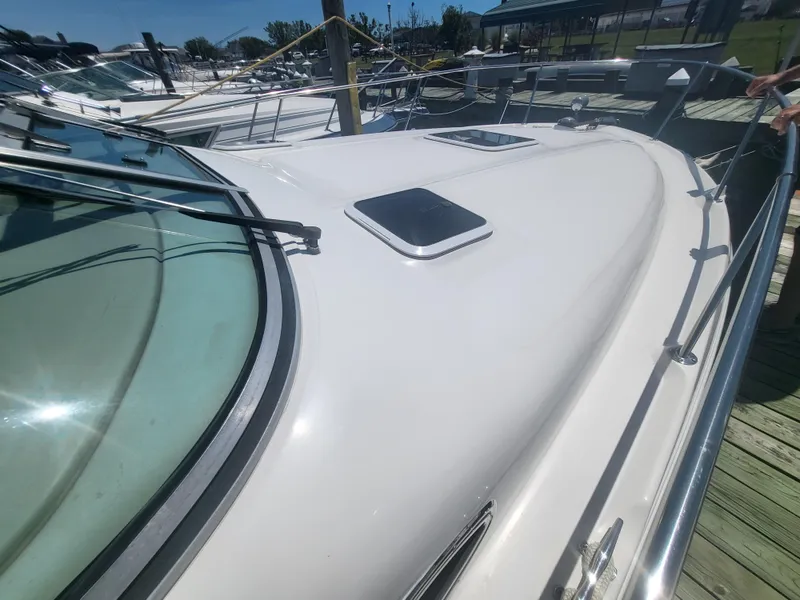 Slide: The Image of 1999 Sea Ray 290 Sundancer boat docked, showcasing sleek deck and windows. - 36
