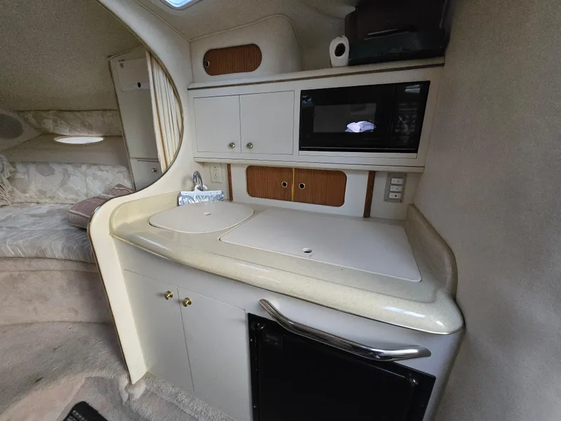 Slide: The Image of 1999 Sea Ray 290 Sundancer cabin with kitchenette, featuring microwave and storage cabinets. - 40