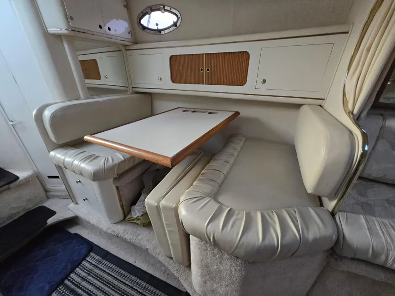 Slide: The Image of 1999 Sea Ray 290 Sundancer cabin interior with dining area and cushioned seating. - 42