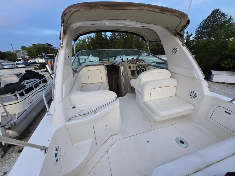 Slide: The Image of 1999 Sea Ray 290 Sundancer boat interior with seating and control panel, docked outdoors. - 48