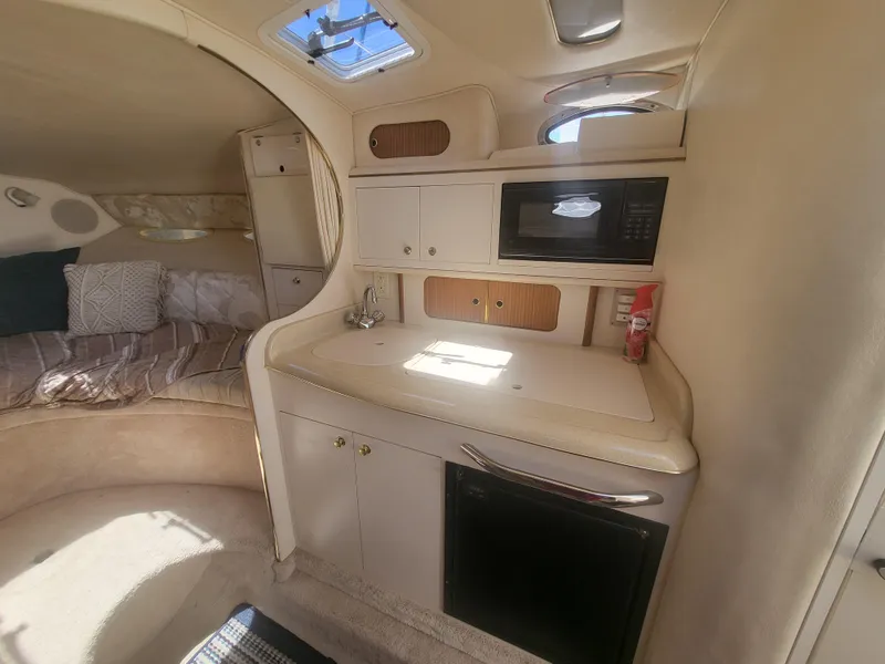 Slide: The Image of 1999 Sea Ray 290 Sundancer cabin interior with kitchenette and cozy sleeping area. - 9