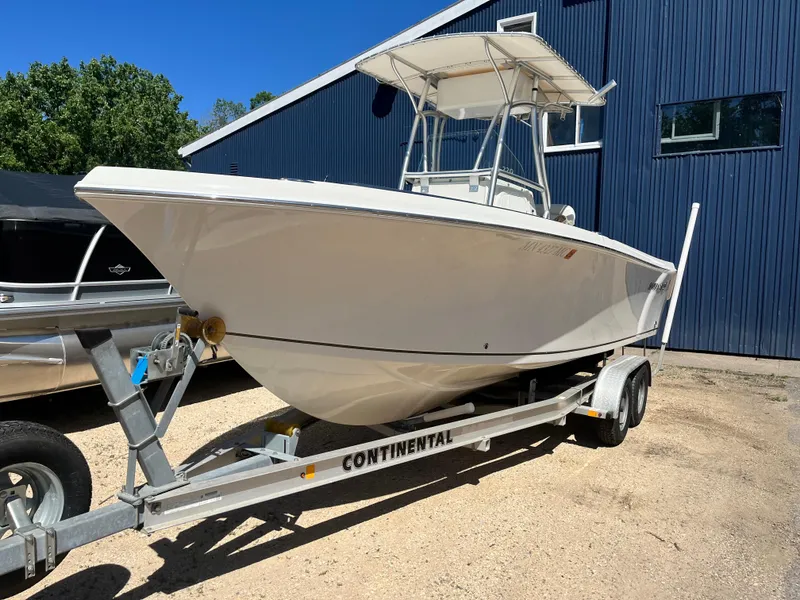 The Image of 2015 Sailfish 220 boat on Continental trailer, parked outdoors near a blue building. - 0