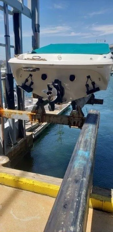 Slide: The Image of 1998 Baja 252I boat being lifted from the water at a marina. - 3
