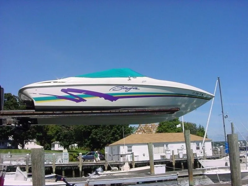 Slide: The Image of 1998 Baja 252I speedboat docked at a marina with a blue cover. - 7