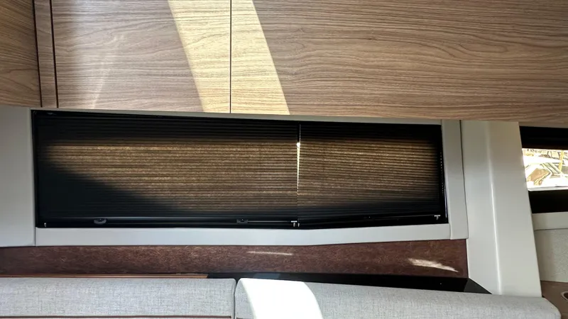 Slide: The Image of 2025 Boston Whaler 365 Conquest interior with wooden cabinets and window blinds. - 34