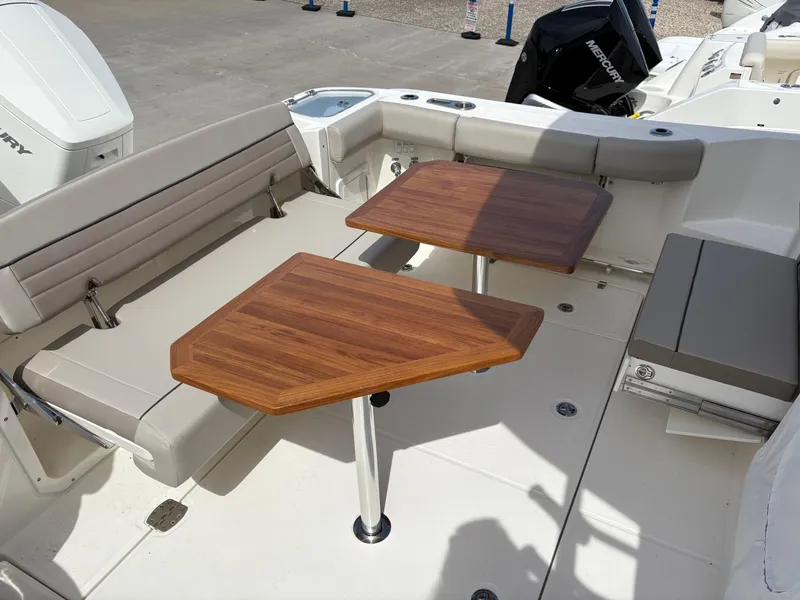 Slide: The Image of 2025 Boston Whaler 365 Conquest boat interior with wooden tables and cushioned seating. - 7