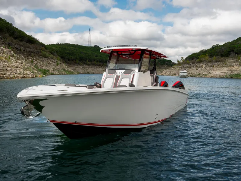 Slide: The Image of 2024 Fountain 32NX boat cruising on a scenic lake with rocky hills. - 0