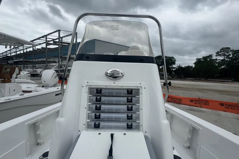 Slide: The Image of 2024 NauticStar 224 Bay boat console with storage compartments, docked under cloudy skies. - 16