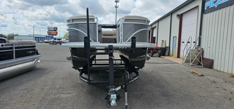 Slide: The Image of 2024 Sun Tracker Party Barge 20 DLX pontoon boat on trailer, parked outside a warehouse. - 3