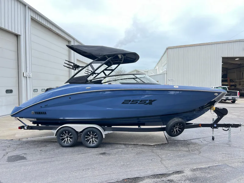 Slide: The Image of 2024 Yamaha Boats 255XD in blue, parked on a trailer outside a warehouse. - 14