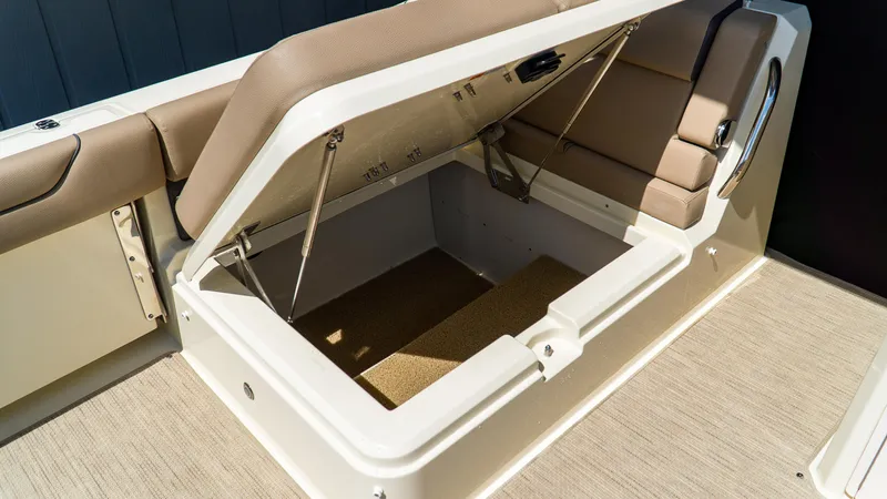 Slide: The Image of 2025 Chris-Craft 32 Calypso boat storage compartment with open lid and cushioned seating. - 17