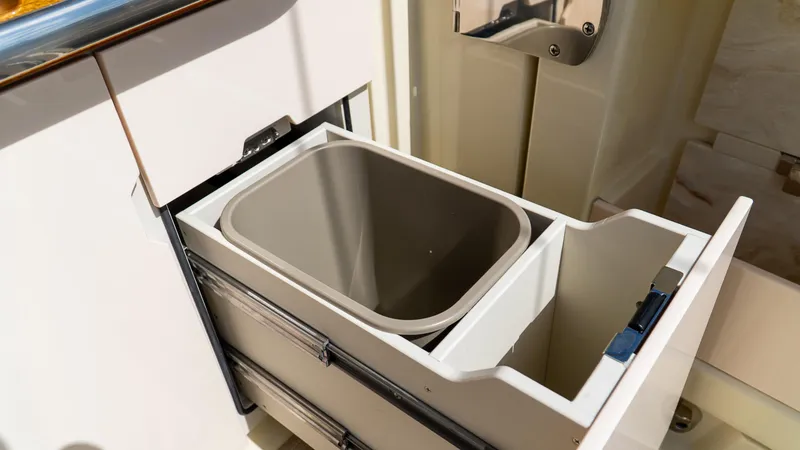 Slide: The Image of 2025 Chris-Craft 32 Calypso boat interior with open storage compartment and trash bin. - 22