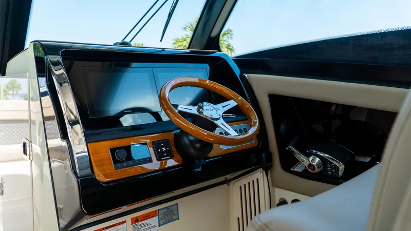 Slide: The Image of 2025 Chris-Craft 32 Calypso helm with wooden steering wheel and modern controls. - 24