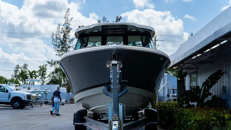 Slide: The Image of 2025 Chris-Craft 32 Calypso boat on trailer, parked outdoors under a cloudy sky. - 3