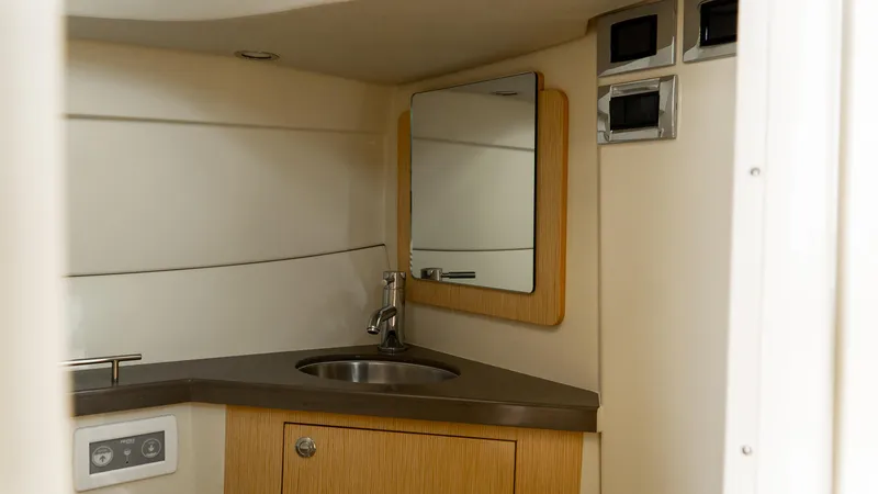Slide: The Image of 2025 Chris-Craft 32 Calypso boat interior with sink, mirror, and wooden cabinetry. - 38