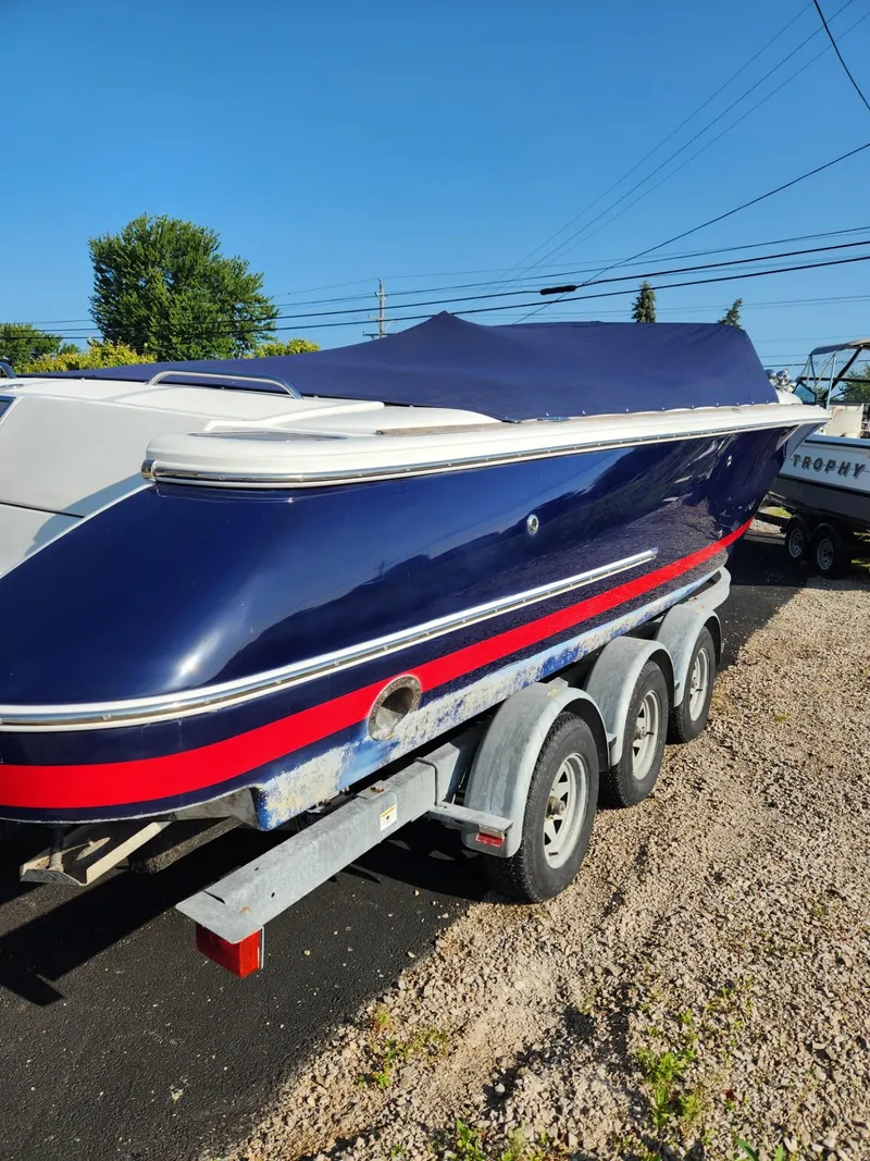 Slide: The Image of 2004 Chris-Craft Launch 28 boat on a trailer, covered with a blue tarp. - 2