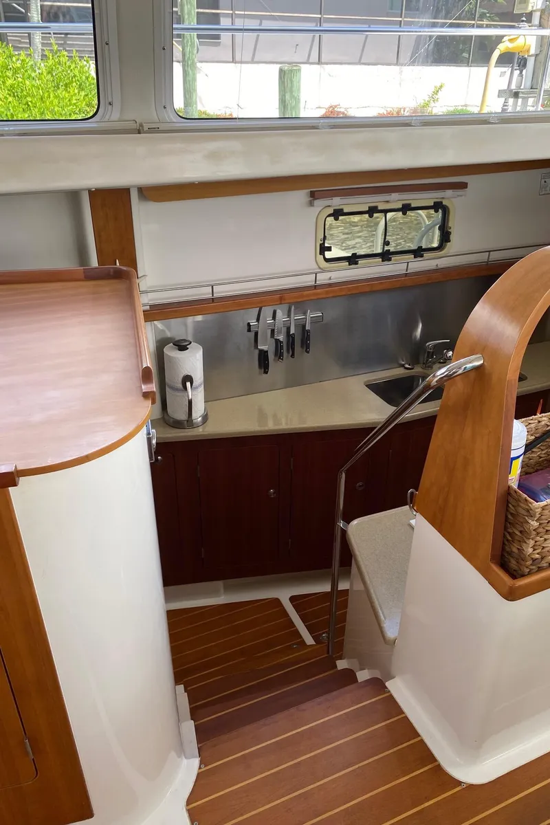 Slide: The Image of Open wooden cabinet on PDQ MV-41 boat, displaying shelves with various items, 2008 model. - 17