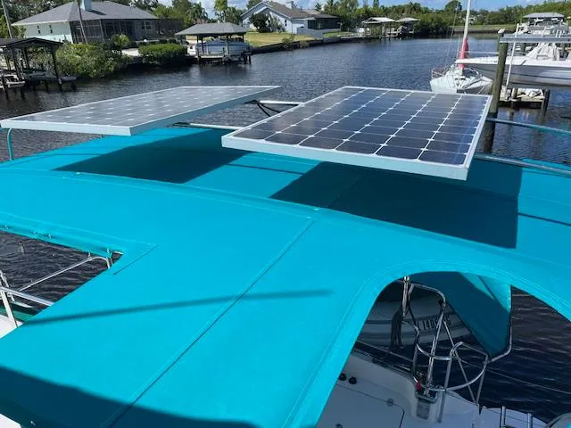 Slide: The Image of Deck of 2008 PDQ MV-41 boat with seating and teal canopy, near water. - 54