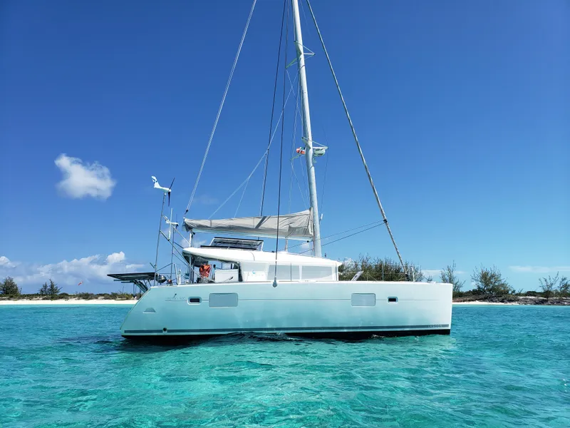 The Image of 2010 Lagoon 400 owner's version catamaran sailing in clear turquoise waters near a sandy beach. - 0