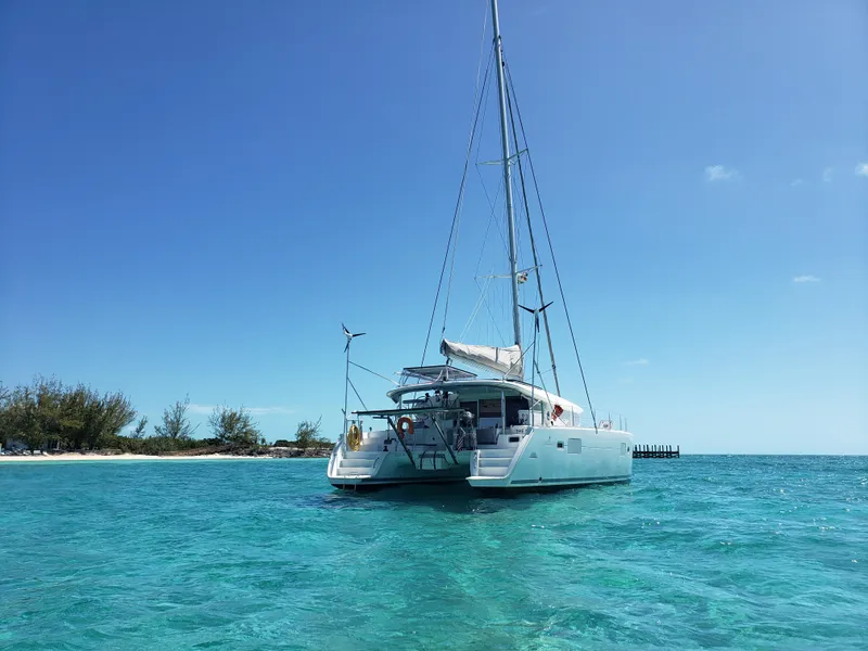 Slide: The Image of 2010 Lagoon 400 owner's version catamaran anchored in clear turquoise waters near a sandy beach. - 10
