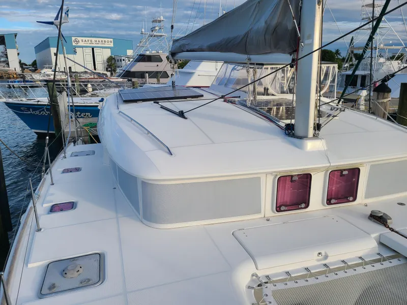 Slide: The Image of 2010 Lagoon 400 owner's version catamaran docked at marina, showcasing deck and sail. - 14