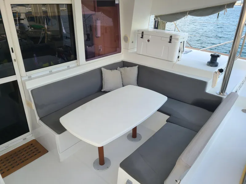 Slide: The Image of Lagoon 400 catamaran cockpit with cushioned seating and table, 2010 model, ocean view. - 28