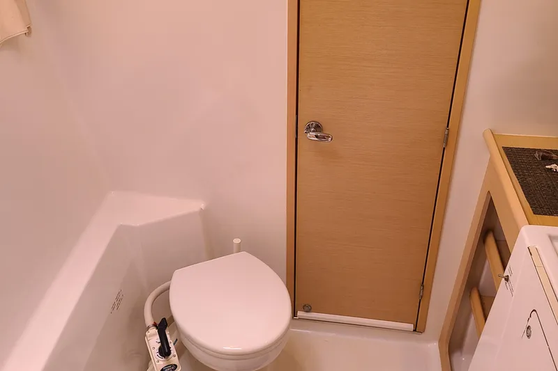 Slide: The Image of Bathroom interior of 2010 Lagoon 400 owner's version catamaran, featuring toilet and wooden door. - 42