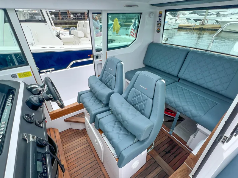 Slide: The Image of 2022 Axopar 28 Cabin Aft Cabin interior with blue seating and wood flooring. - 14