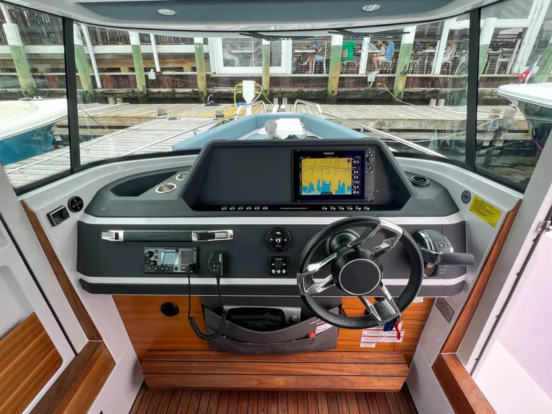 Slide: The Image of 2022 Axopar 28 Cabin Aft Cabin helm with navigation display and steering wheel. - 17