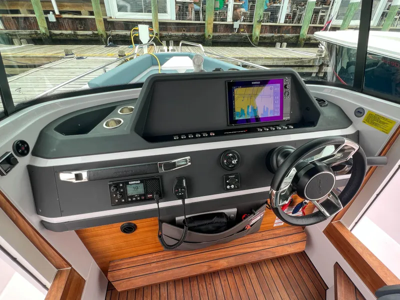 Slide: The Image of 2022 Axopar 28 Cabin Aft Cabin helm with modern navigation system and sleek steering wheel. - 18