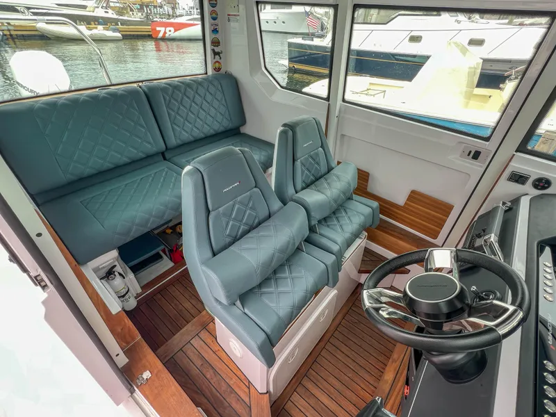 Slide: The Image of 2022 Axopar 28 Cabin Aft Cabin interior with plush seating and modern steering wheel. - 19