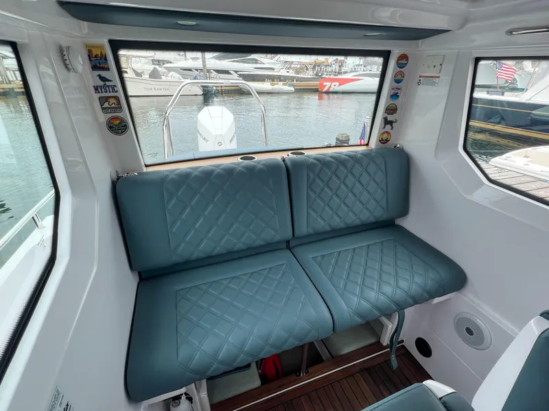 Slide: The Image of 2022 Axopar 28 Cabin Aft Cabin interior with blue quilted seating and marina view. - 20