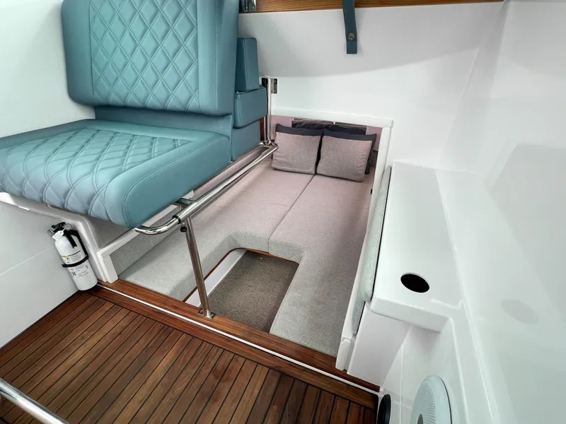Slide: The Image of 2022 Axopar 28 Cabin Aft Cabin interior with blue seating and wood flooring. - 22