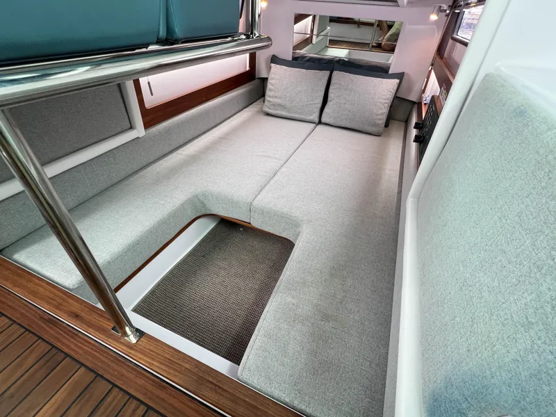 Slide: The Image of 2022 Axopar 28 Cabin Aft Cabin interior with gray cushions and wooden flooring. - 23