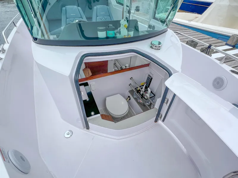 Slide: The Image of 2022 Axopar 28 Cabin Aft Cabin boat with open hatch revealing interior toilet. - 25