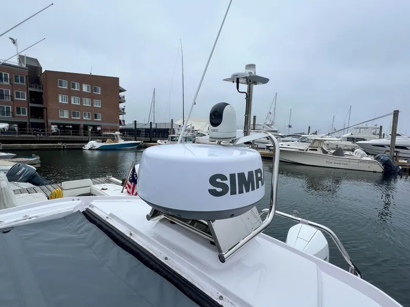 Slide: The Image of 2022 Axopar 28 Cabin Aft Cabin docked, featuring Simrad radar, marina background. - 27