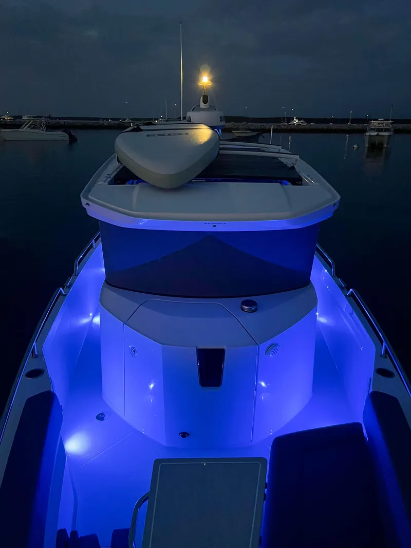 Slide: The Image of 2022 Axopar 28 Cabin Aft Cabin boat with blue LED lights at night. - 29