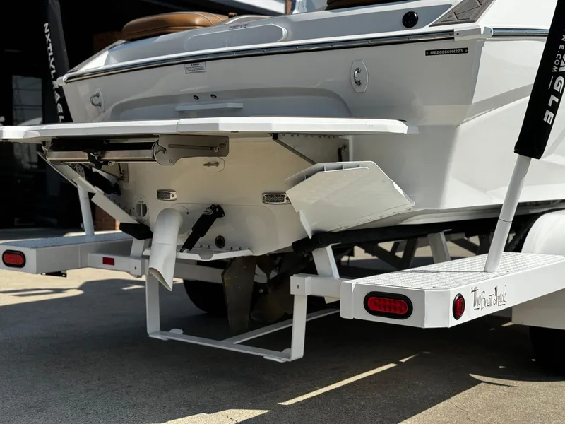 Slide: The Image of 2023 MB SPORTS B52 23 Alpha boat rear view on trailer, showcasing propeller and platform. - 4
