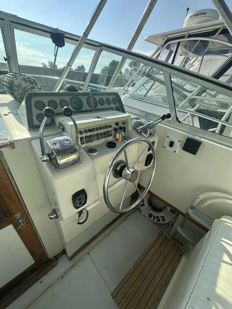 Slide: The Image of 1984 Aquasport 270 Express Fisherman boat cockpit with steering wheel and control panel. - 11