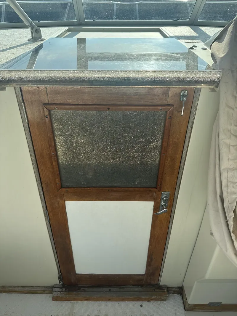 Slide: The Image of 1984 Aquasport 270 Express Fisherman cabin door with wooden frame and mesh screen. - 13