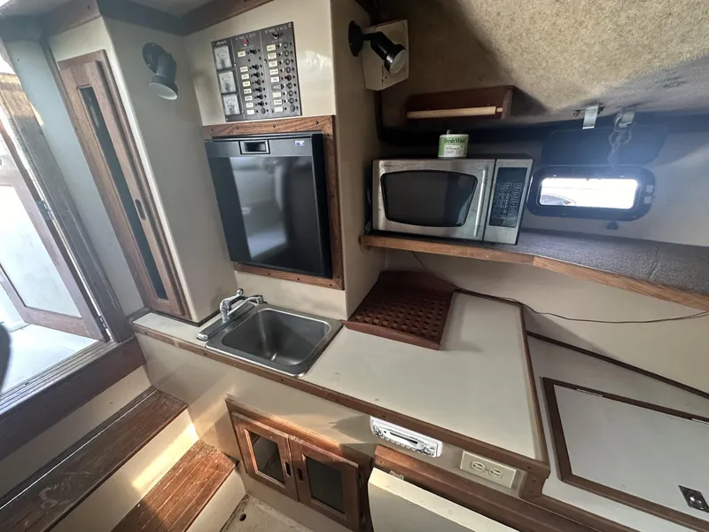 Slide: The Image of 1984 Aquasport 270 Express Fisherman galley with sink, microwave, and storage. - 16