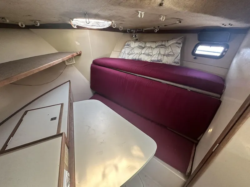 Slide: The Image of Interior cabin of a 1984 Aquasport 270 Express Fisherman with red cushions and a small table. - 18