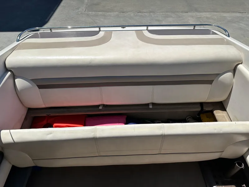 Slide: The Image of 1998 Chaparral 2335 SS boat with open storage compartment and cushioned seating. - 16