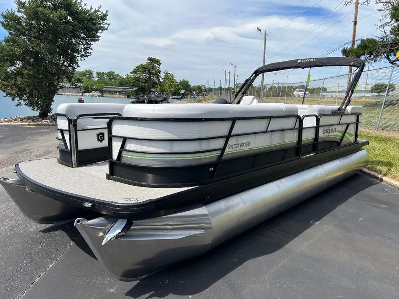 Slide: The Image of 2023 Godfrey Sweetwater 2486 C pontoon boat on pavement near water. - 2