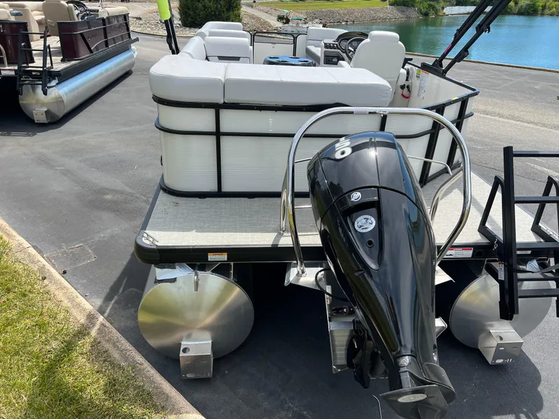 Slide: The Image of 2023 Godfrey Sweetwater 2486 C pontoon boat with outboard motor, docked near a lake. - 6