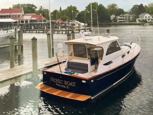 Slide: The Image of 2003 Legacy Yachts 34 Sedan docked at a marina, surrounded by calm water and scenic buildings. - 10