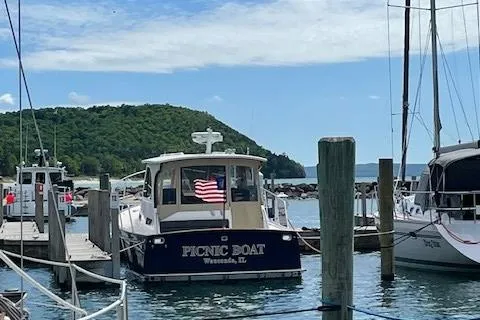 Slide: The Image of 2003 Legacy Yachts 34 Sedan docked, displaying an American flag, with scenic background. - 14
